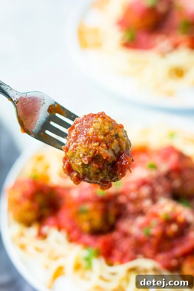 fork holding a meatball drenched in marinara
