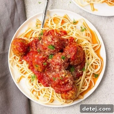 meatballs with red sauce on spaghetti on a plate with grey background