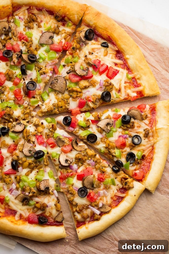 Cooked pizza with veggies, cheese, tempeh sausage, and tomato sauce