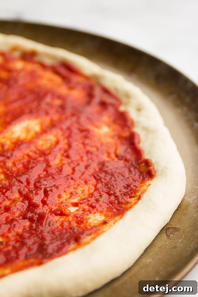 Close up of raw pizza dough covered in tomato sauce