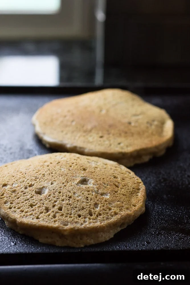 Flipping fluffy whole grain pancakes to cook until golden brown.