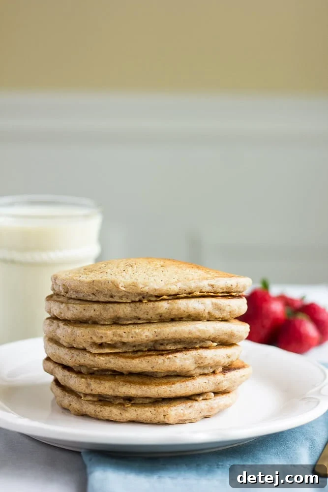 A stack of golden brown Freezer Whole Grain Pancakes served with fresh toppings.
