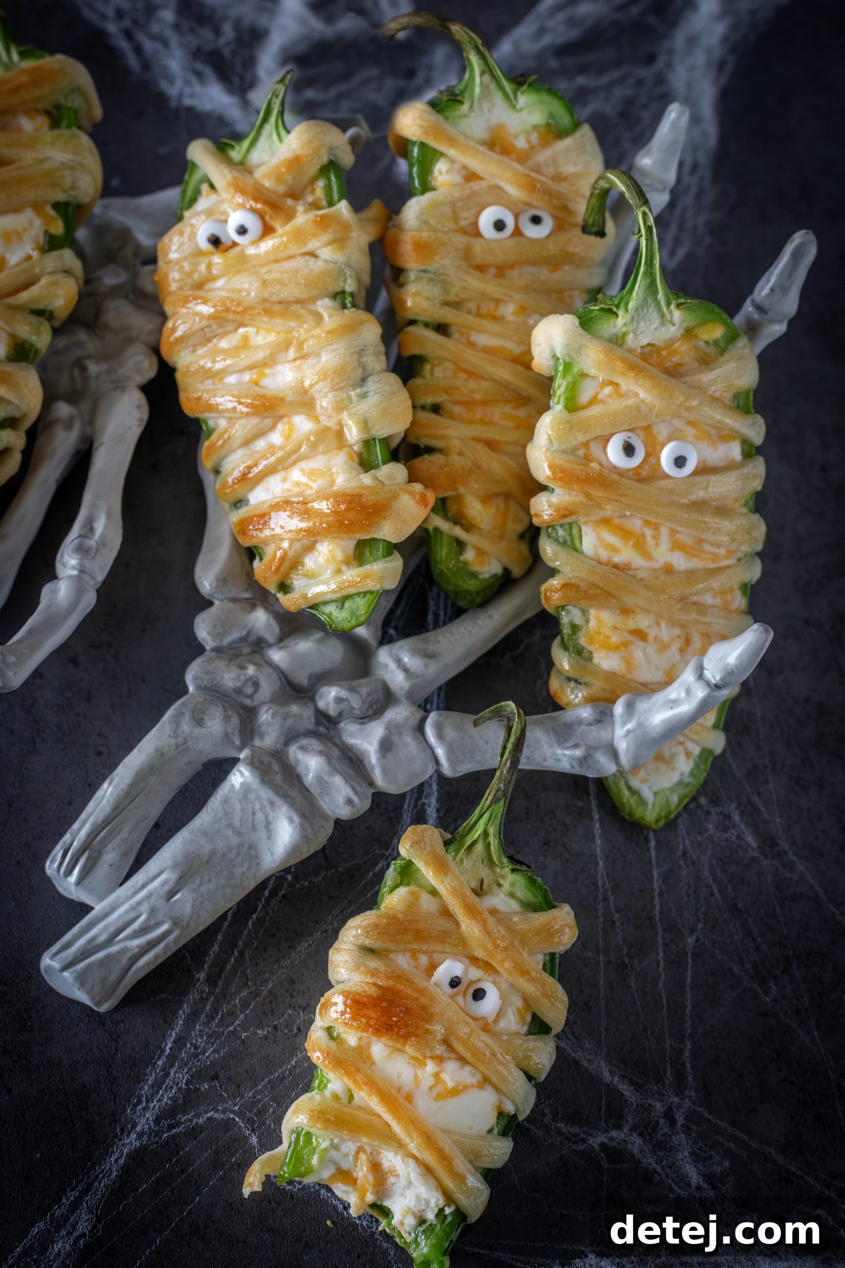 Close-up of freshly baked mummy jalapeno poppers on a serving platter.
