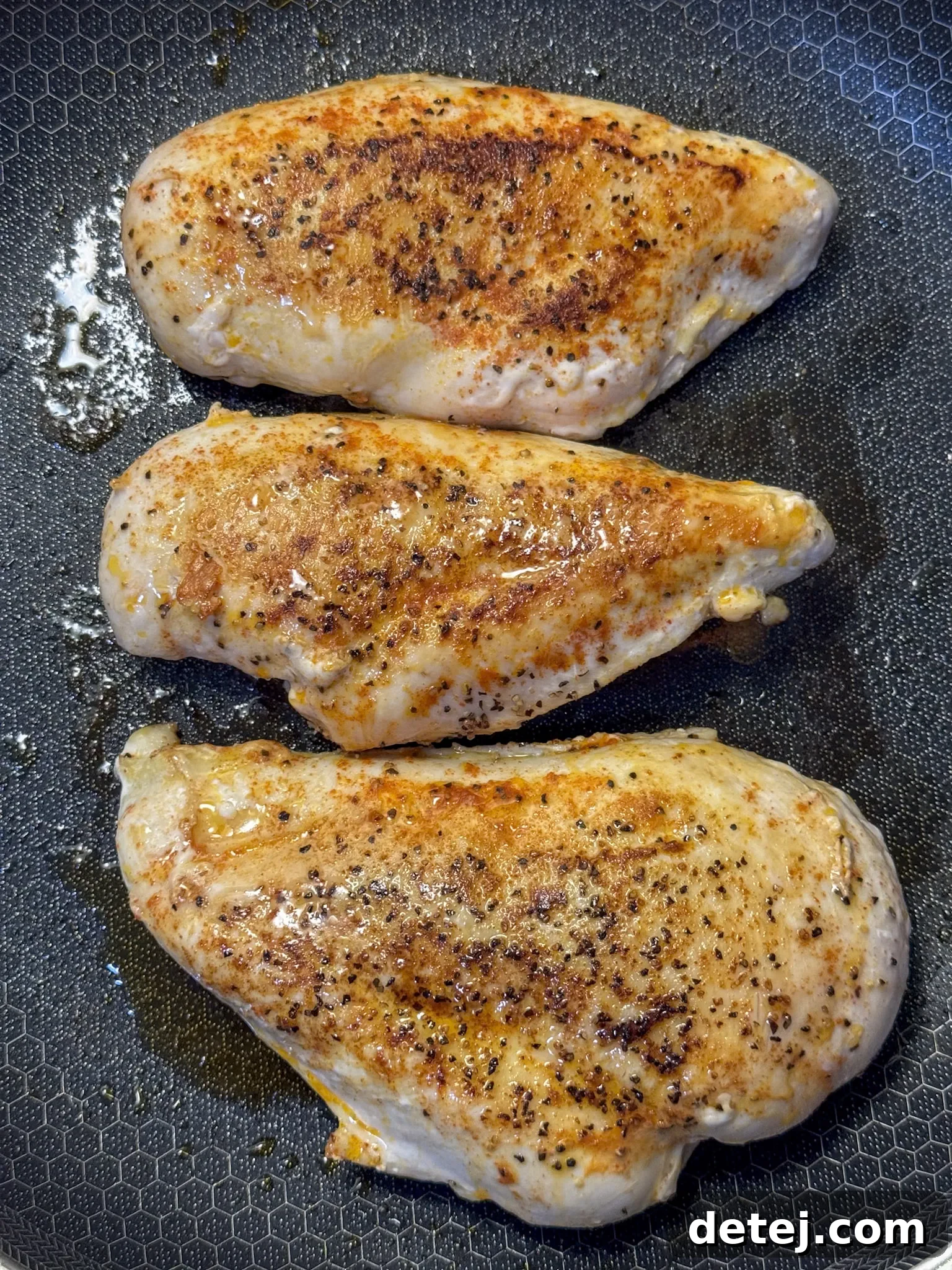 Searing chicken breasts in a hot skillet until golden brown for Alice Springs Chicken, showing the beautiful crust.