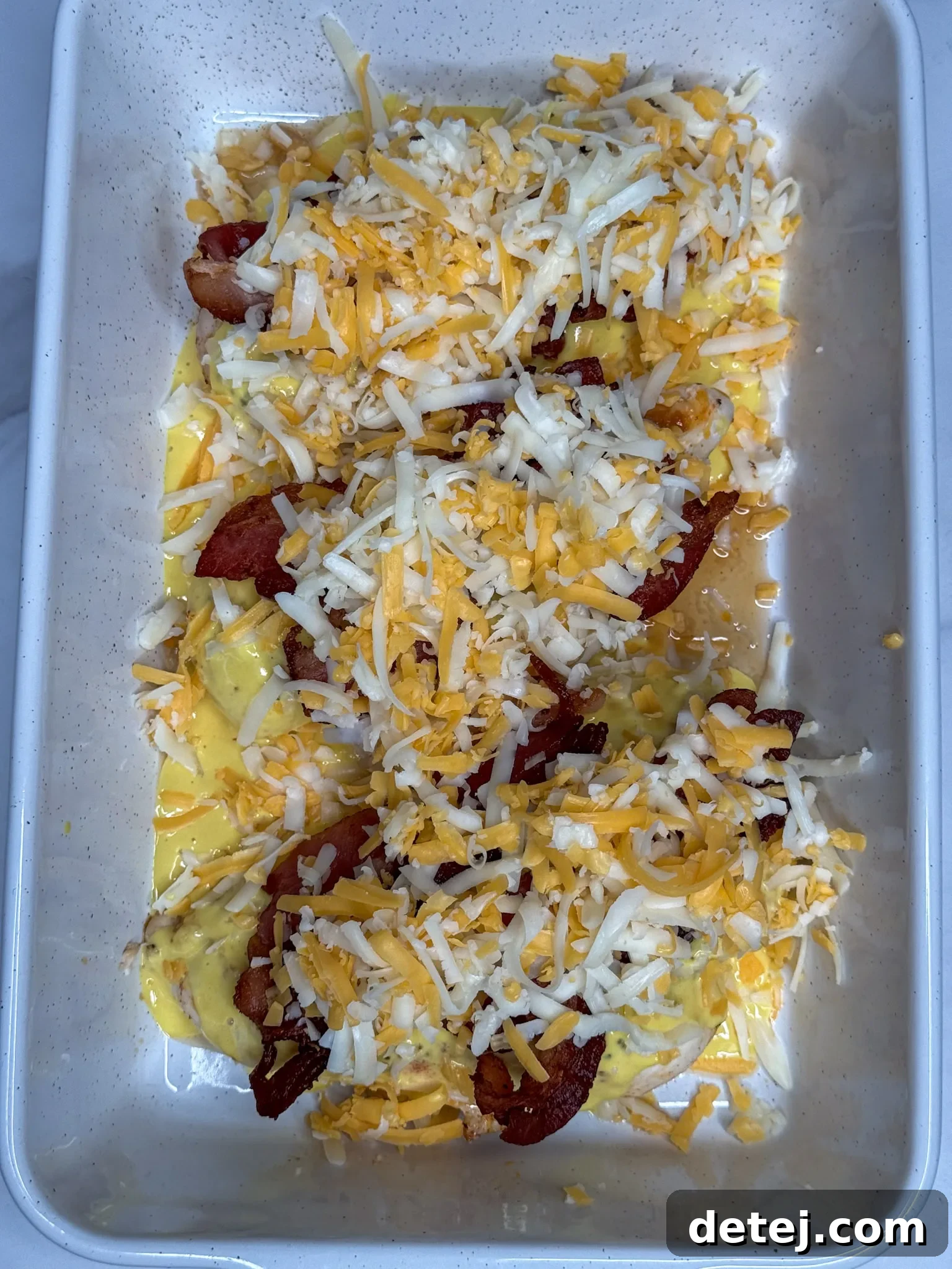 Alice Springs Chicken ready to be baked with honey mustard, Colby Jack cheese, and crispy bacon, showing the final preparation.