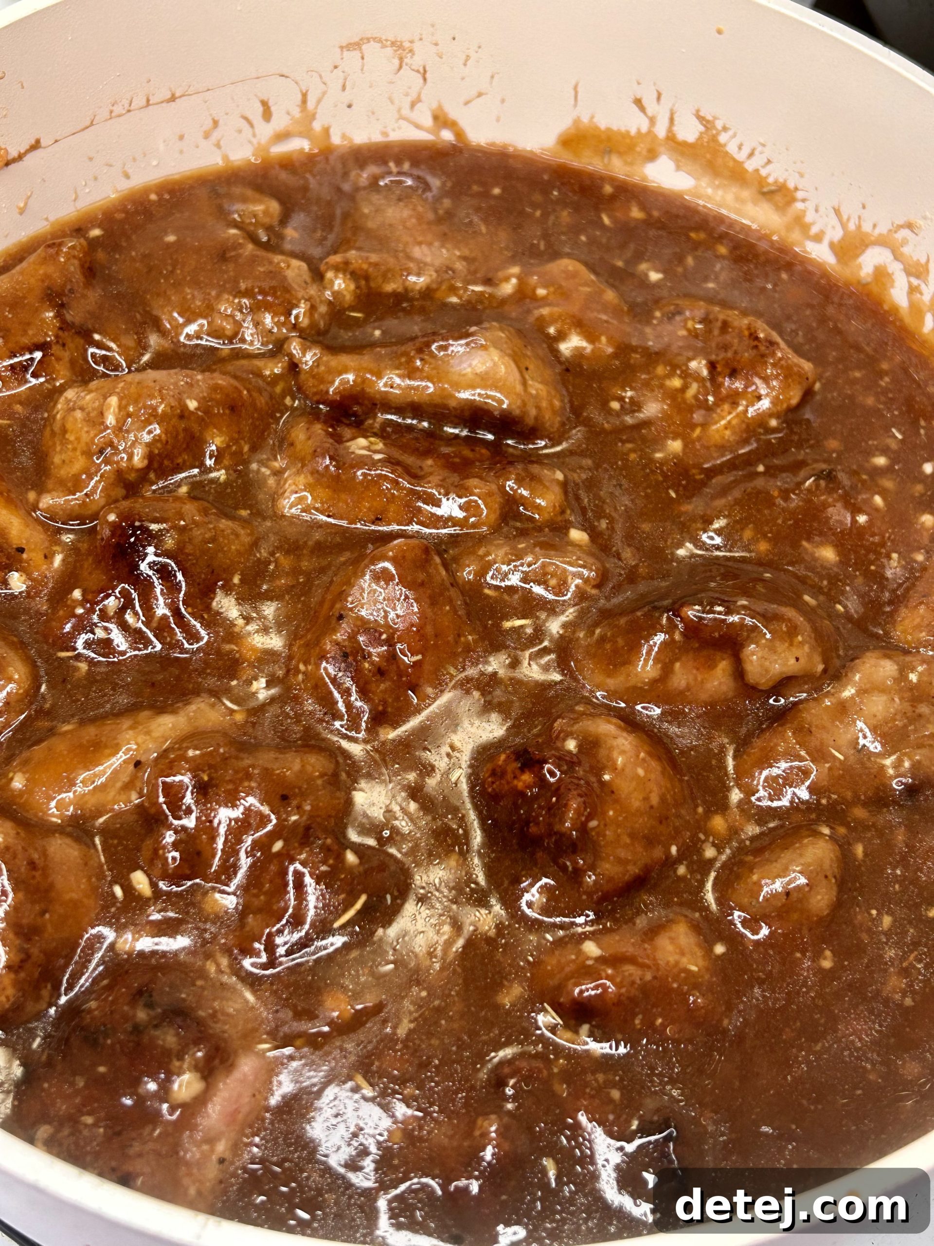 A complete plate of beef tips and gravy served with mashed potatoes and green beans.