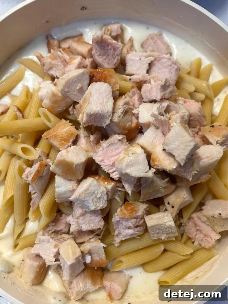 Assembling Chicken Alfredo Bake in a baking dish