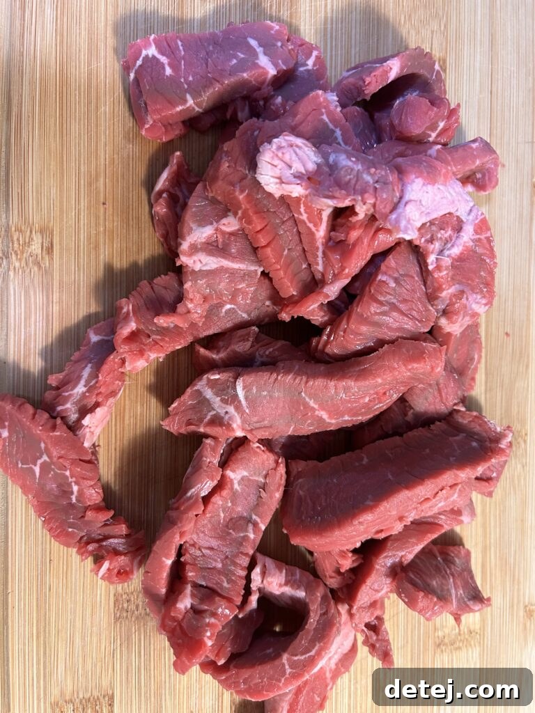 Fresh ingredients for Jamaican Pepper Steak, including sirloin steak, colorful bell peppers, and various herbs.
