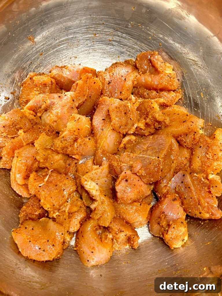 Chicken pieces marinating in a bowl with lemon, pepper, and spices.