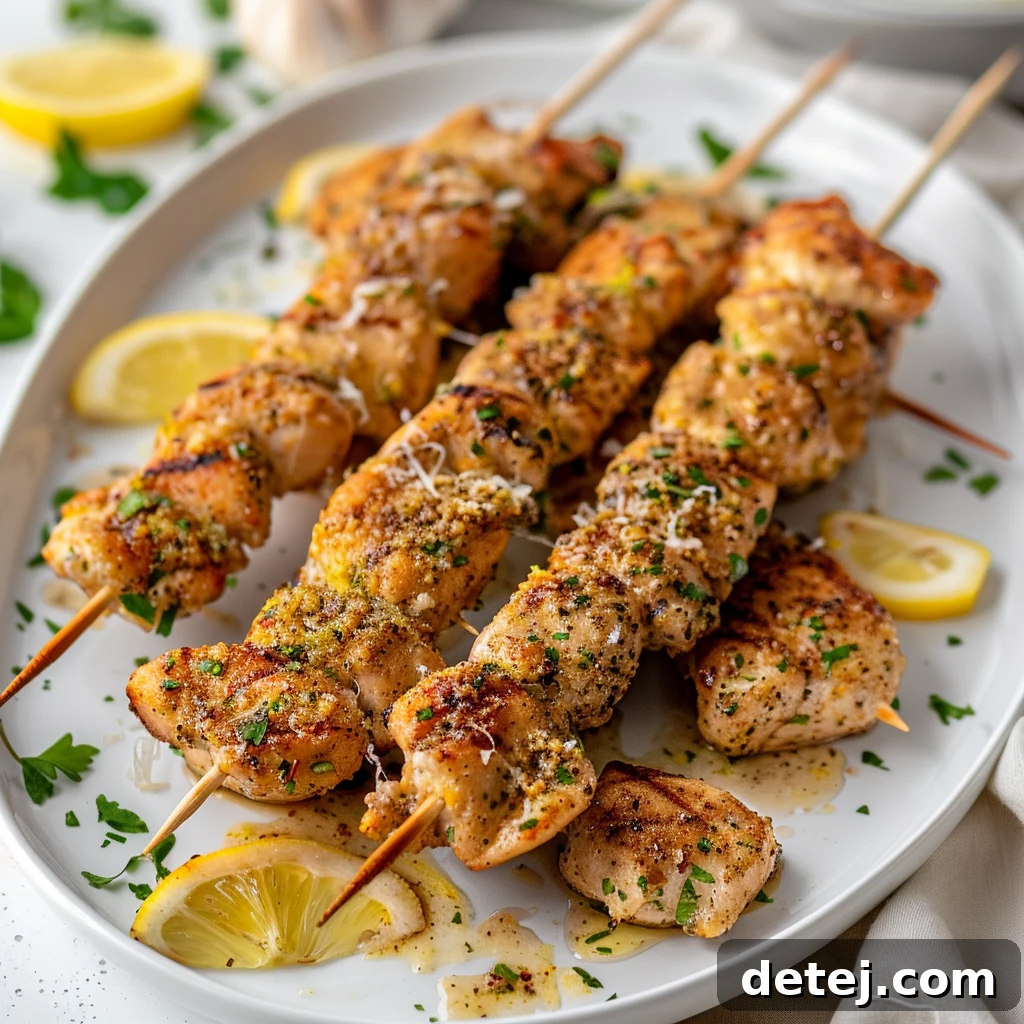 Plated oven-baked lemon pepper chicken skewers with rice and vegetables.