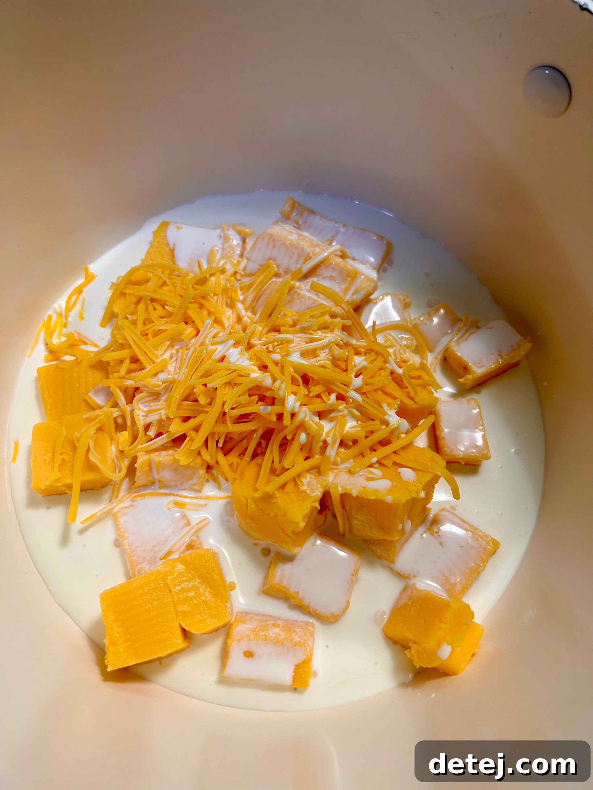 Melting Velveeta cheese and heavy cream in a saucepan