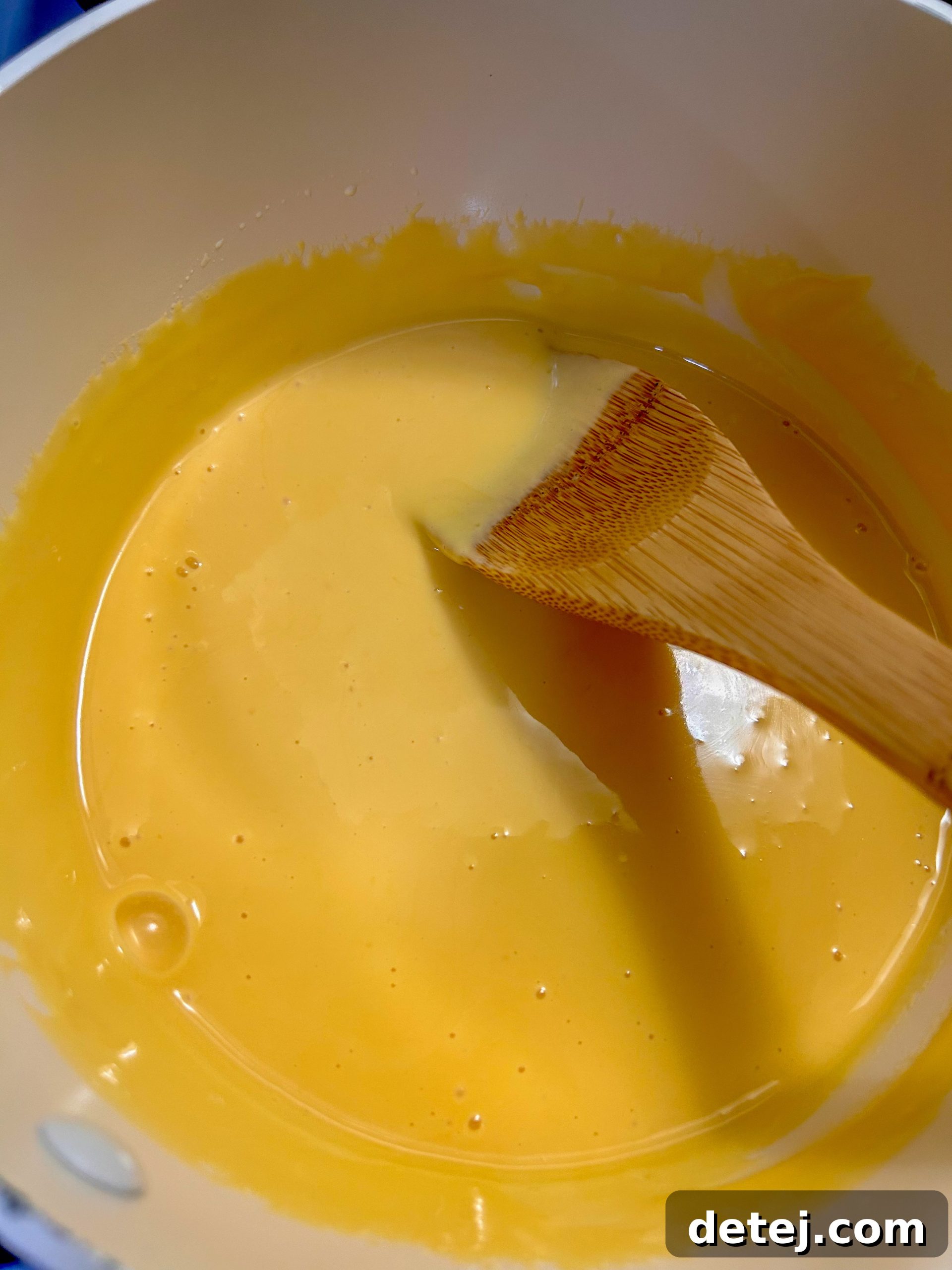 Mixing cooked macaroni with creamy cheese sauce