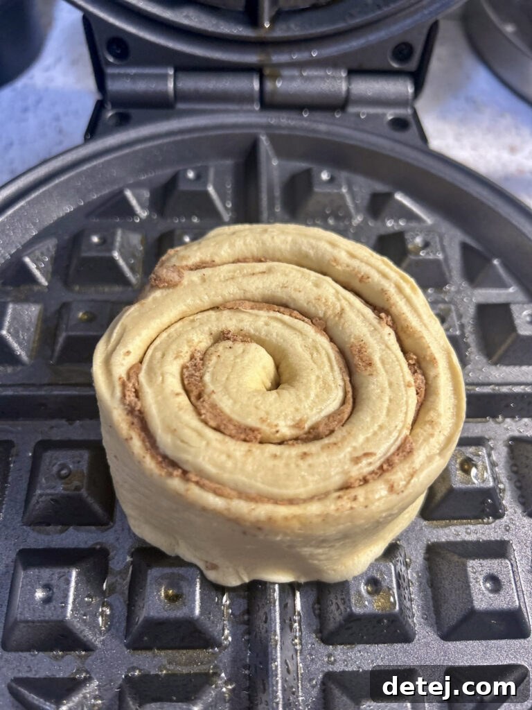 Cinnamon roll cooking in a waffle iron, transforming into a waffle.
