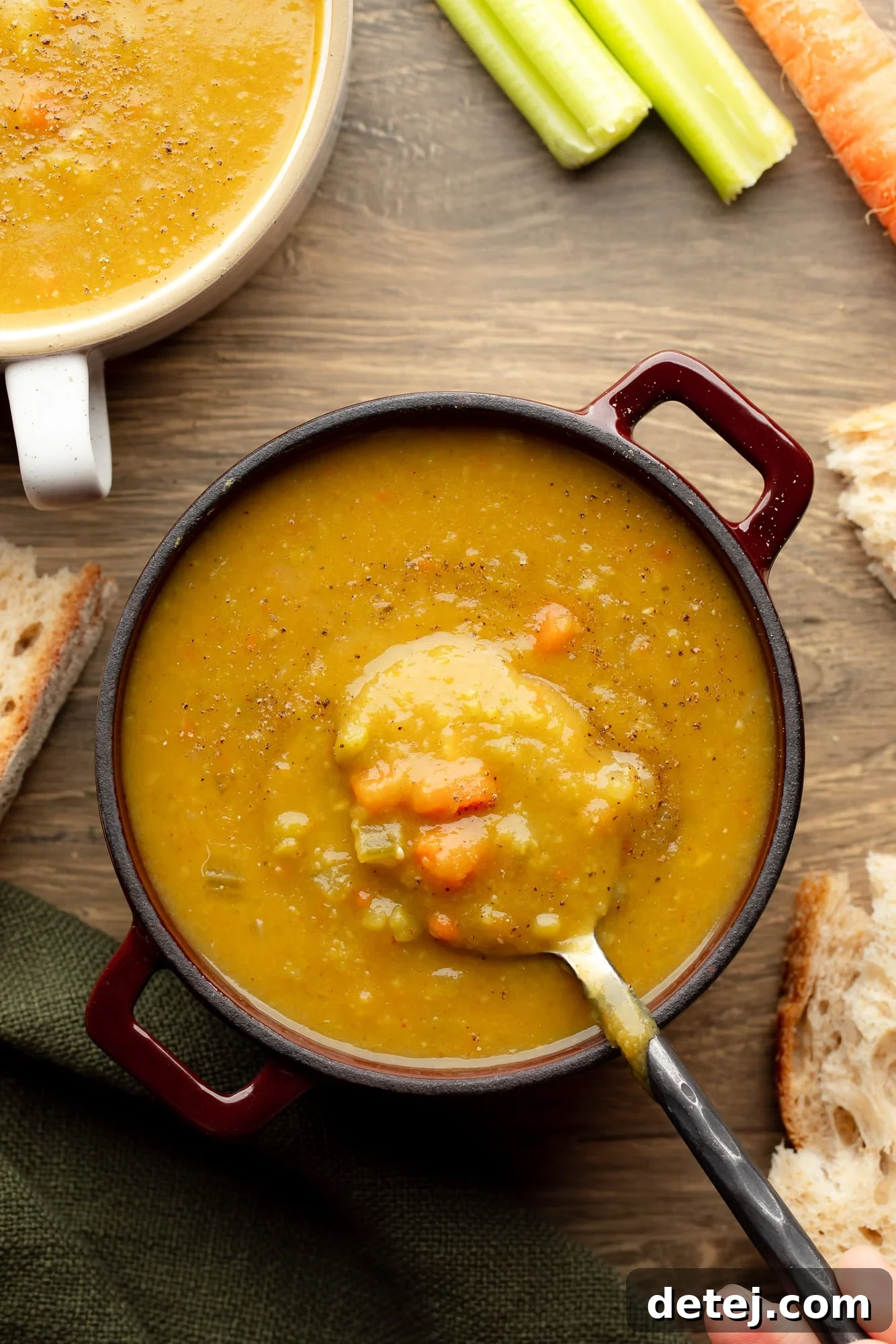 overhead view of a spoon being lifted out of a bowl of vegan split pea soup.