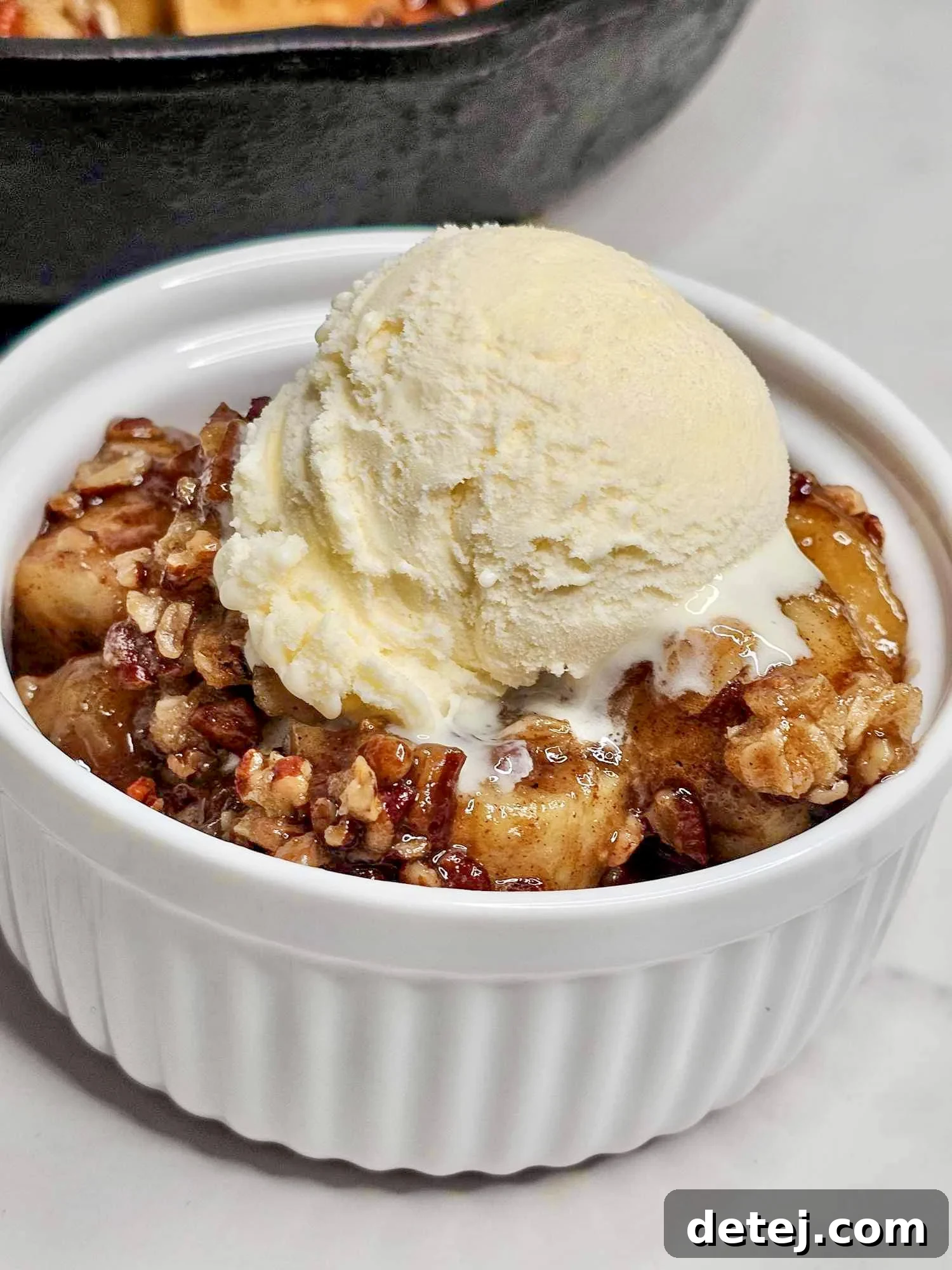 Portion of banana crumble with melting vanilla ice cream