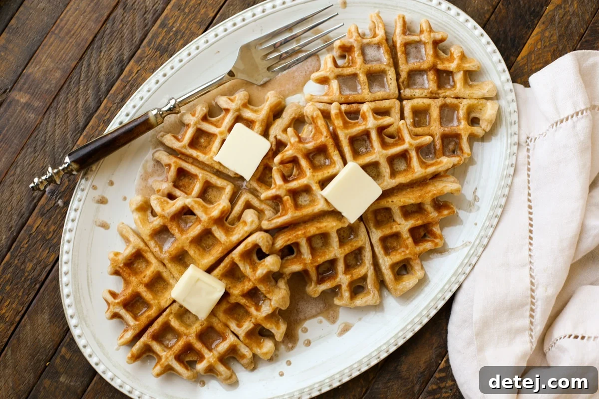 Fluffy Cinnamon Roll Waffles topped with a sweet vanilla glaze, ready to be served for breakfast.