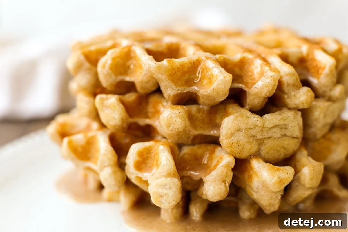 A bowl of creamy vanilla cinnamon glaze next to a whisk, ready to top fresh waffles.