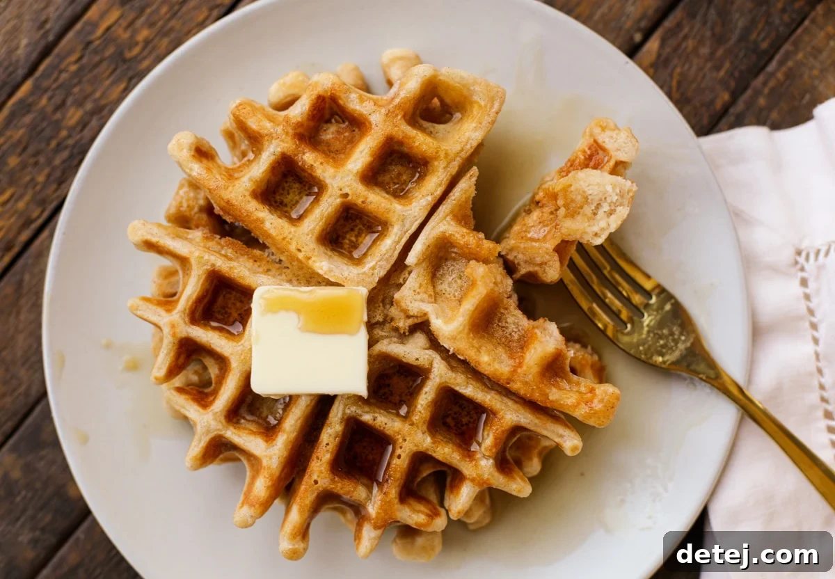 A stack of cinnamon roll waffles garnished with fresh berries and extra glaze, ready for serving.