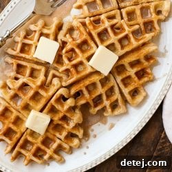 A stack of golden cinnamon roll waffles generously drizzled with vanilla glaze, ready for breakfast.