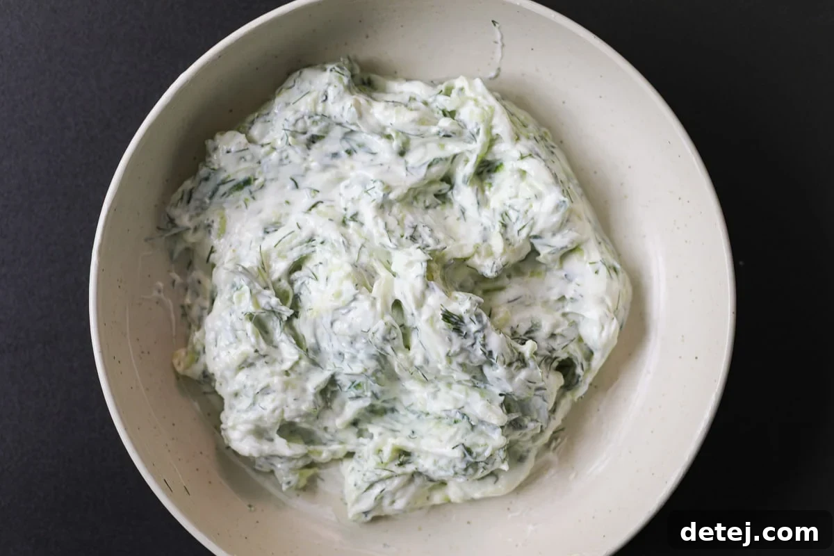 A bowl of easy homemade tzatziki sauce, garnished with fresh dill, ready to be served.