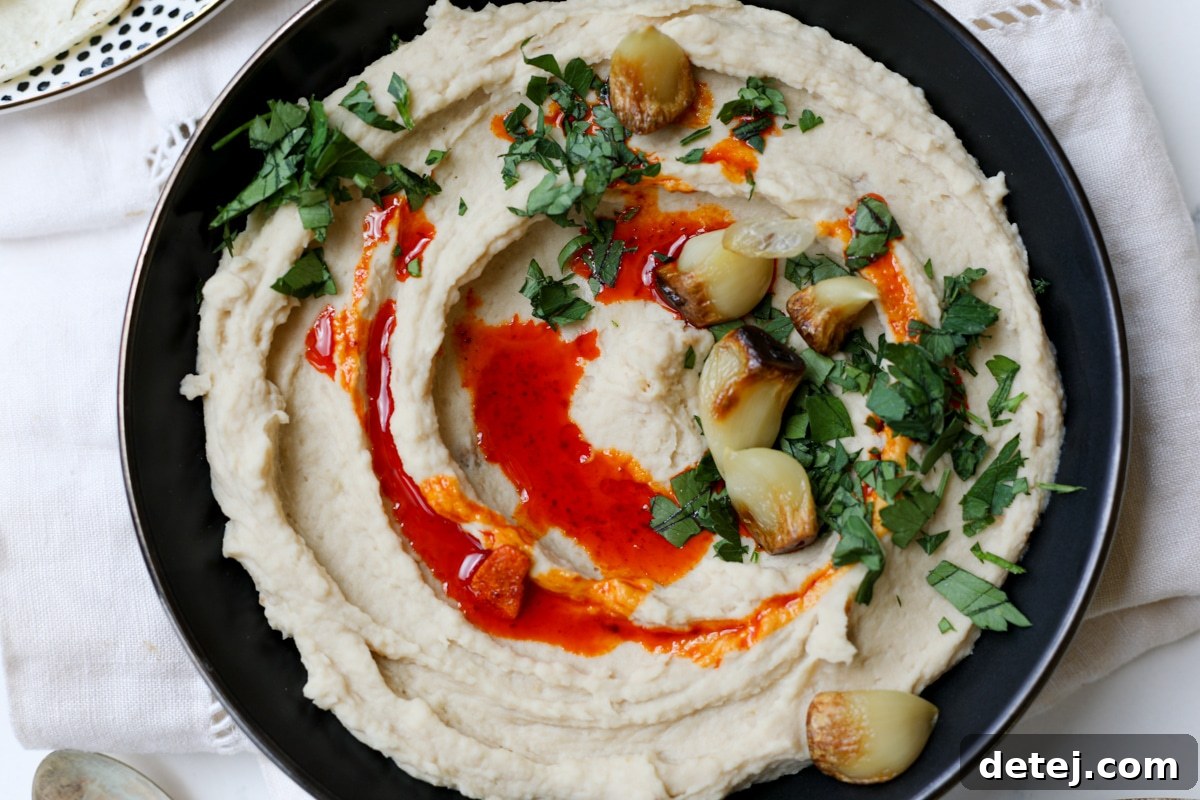 Easy Roasted Garlic White Bean Dip – Healthyish Foods, a close-up of the creamy texture and delicious toppings.