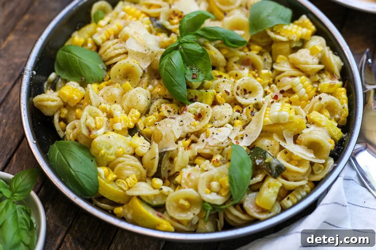 Delicious Summer Pasta with Zucchini, Squash and Corn in a bowl, garnished with basil.
