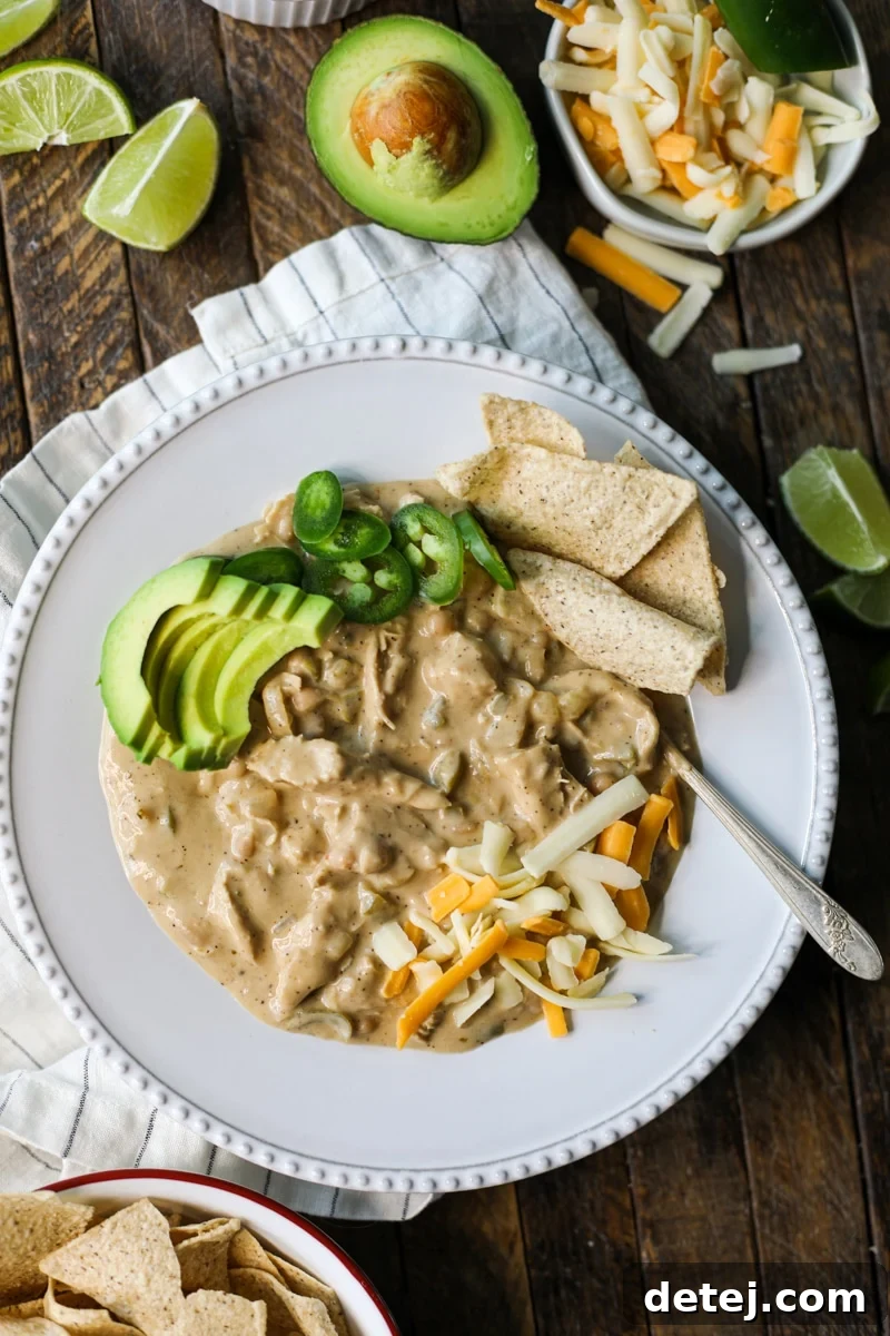 Close-up shot of creamy white chicken chili in a bowl, showing the rich texture, tender chicken, and visible beans.