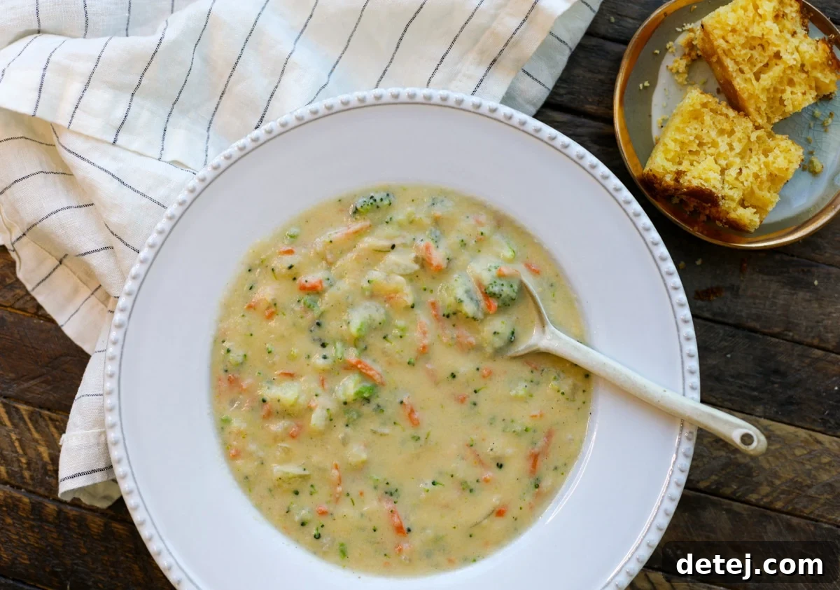 A close-up of healthy broccoli cheddar soup simmering in a large pot, showing the rich, creamy texture and vibrant vegetables.