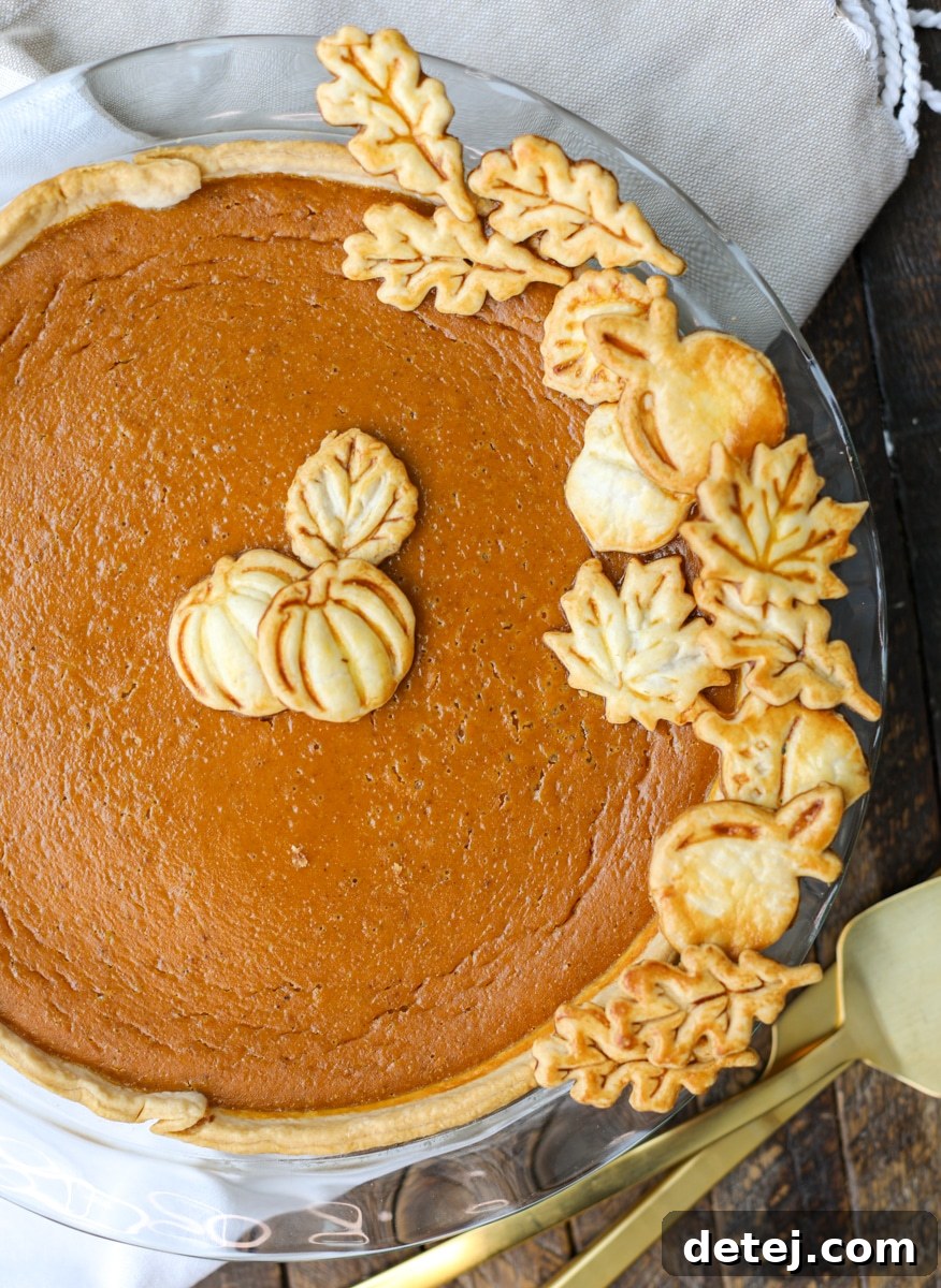 A beautifully homemade pumpkin pie adorned with decorative leaves made from pie crust scraps, perfect for Thanksgiving.
