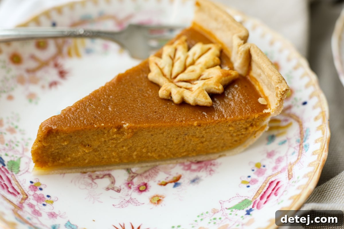 A perfectly sliced piece of pumpkin pie on a decorative plate, ready to be enjoyed.