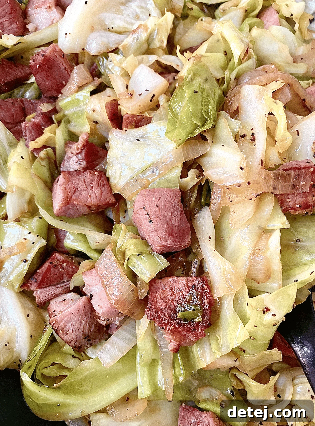 Close-up of a generous serving of Ham and Cabbage, garnished with fresh pepper.