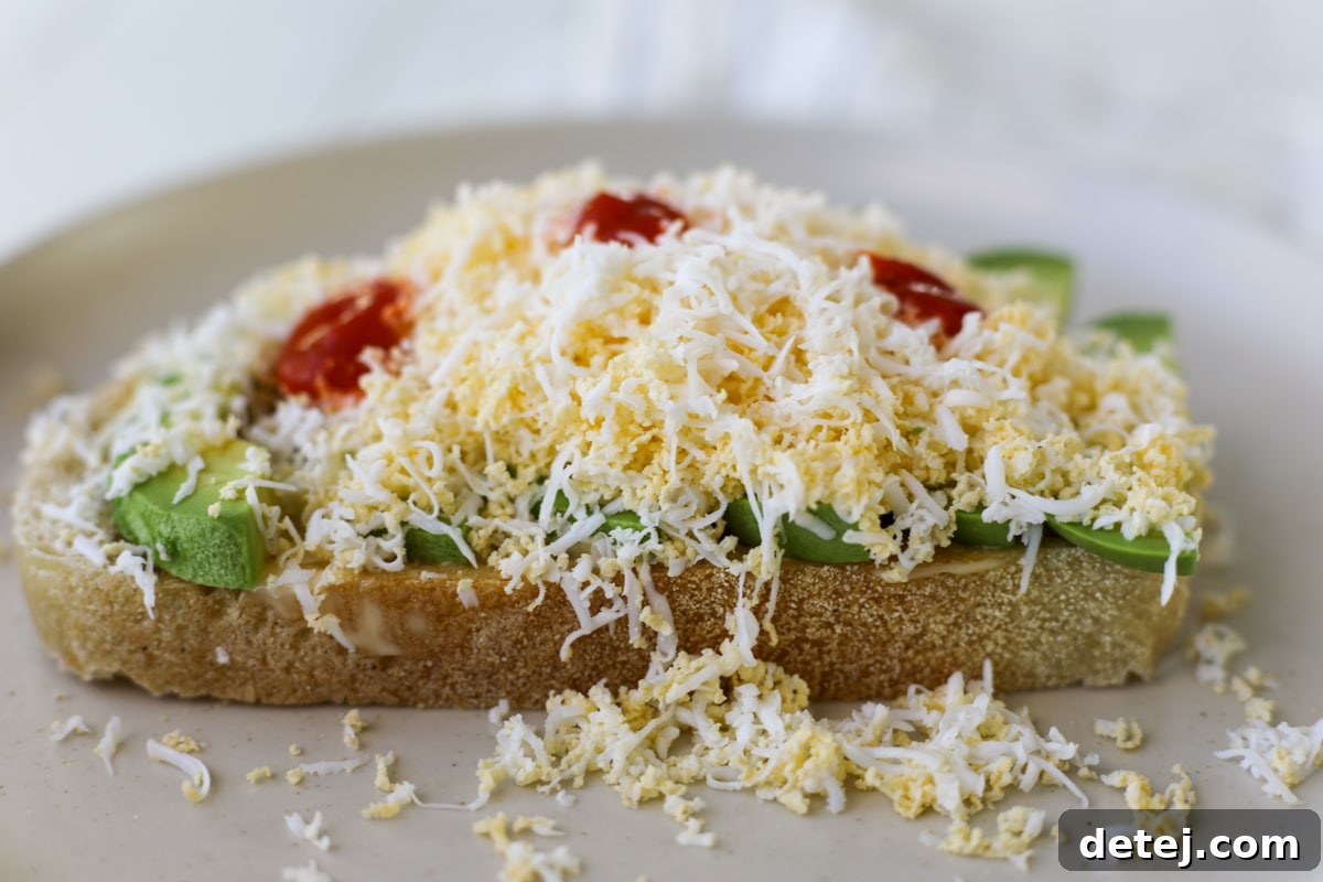 Close-up of freshly grated egg on avocado toast with chili oil