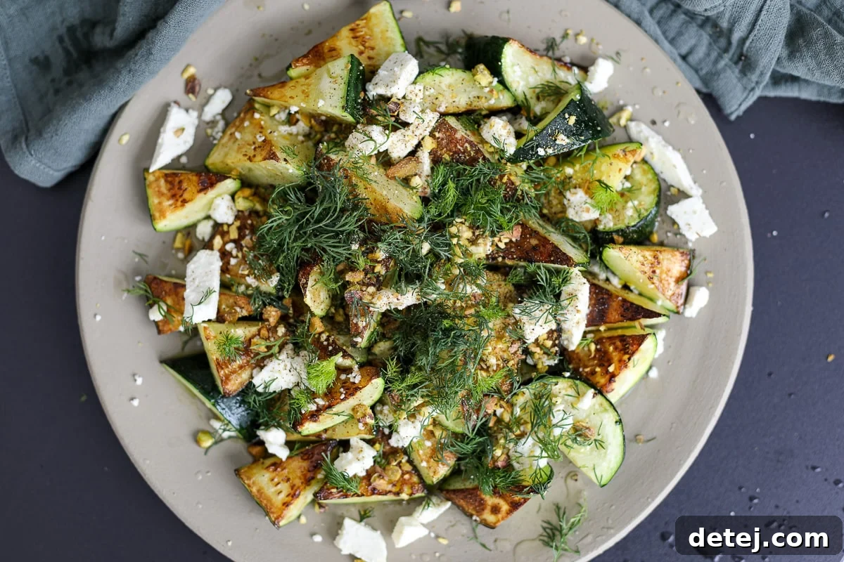 Beautifully pan-fried zucchini garnished with honey, feta, and pistachios on a serving plate.