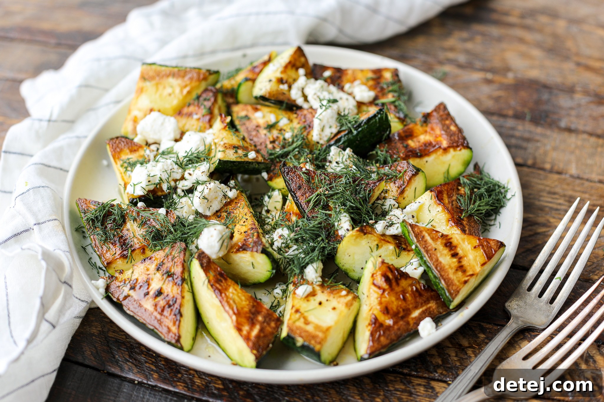 A vibrant platter of pan-fried zucchini, glistening with honey and lemon, topped with white feta and green pistachios.
