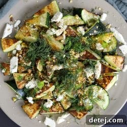 A close-up of pan-fried zucchini, garnished with honey, feta, and pistachios, presented invitingly on a plate.
