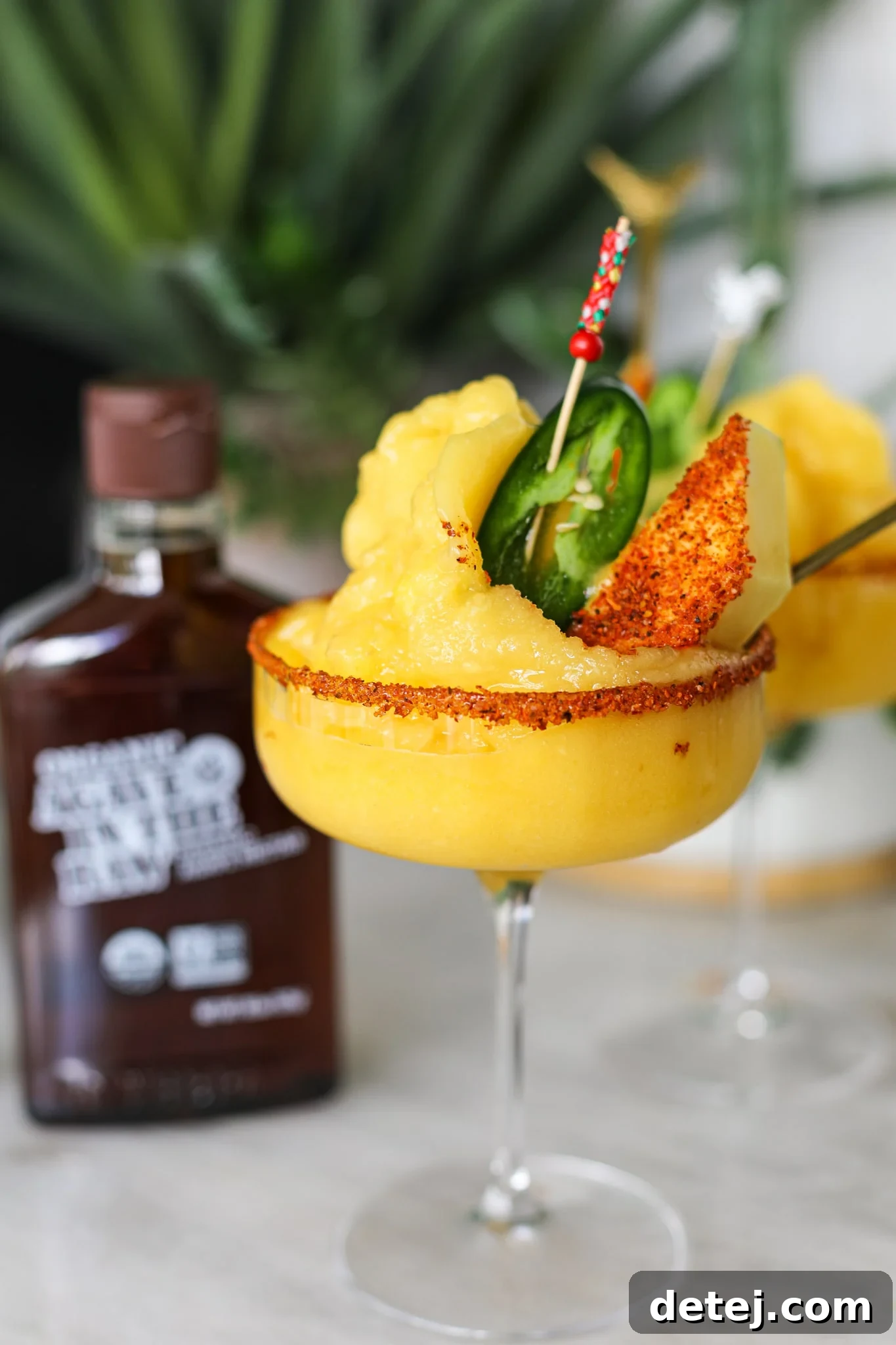 A perfectly blended Frozen Mango Margarita, garnished with fresh mango and a jalapeno slice, ready to be enjoyed.