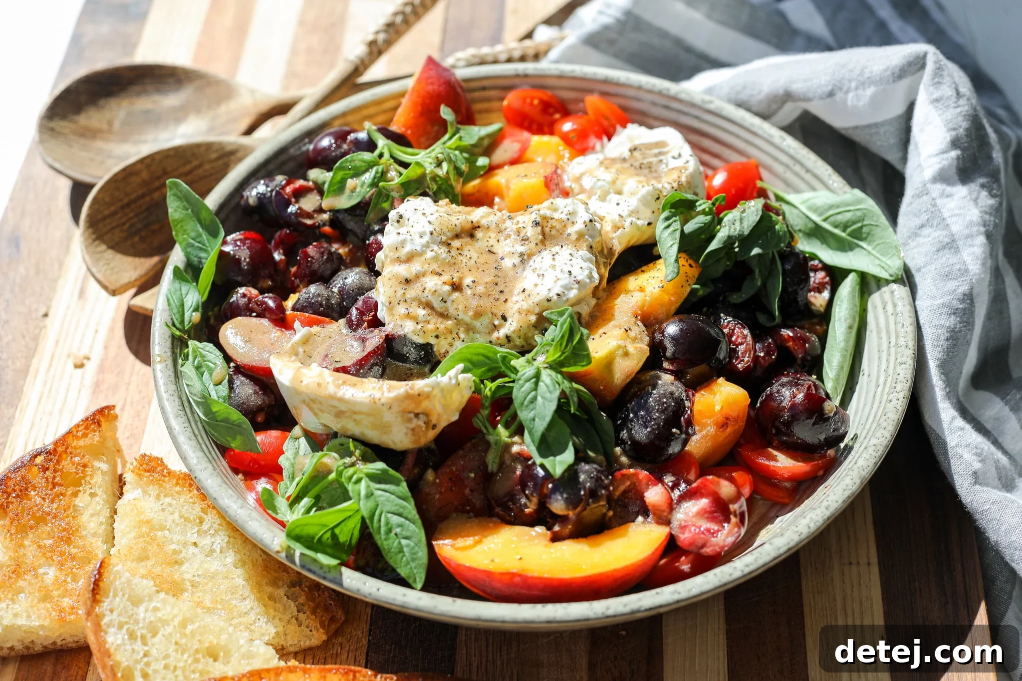 Close-up of fresh burrata cheese nestled among ripe peaches, sweet cherries, and juicy tomatoes