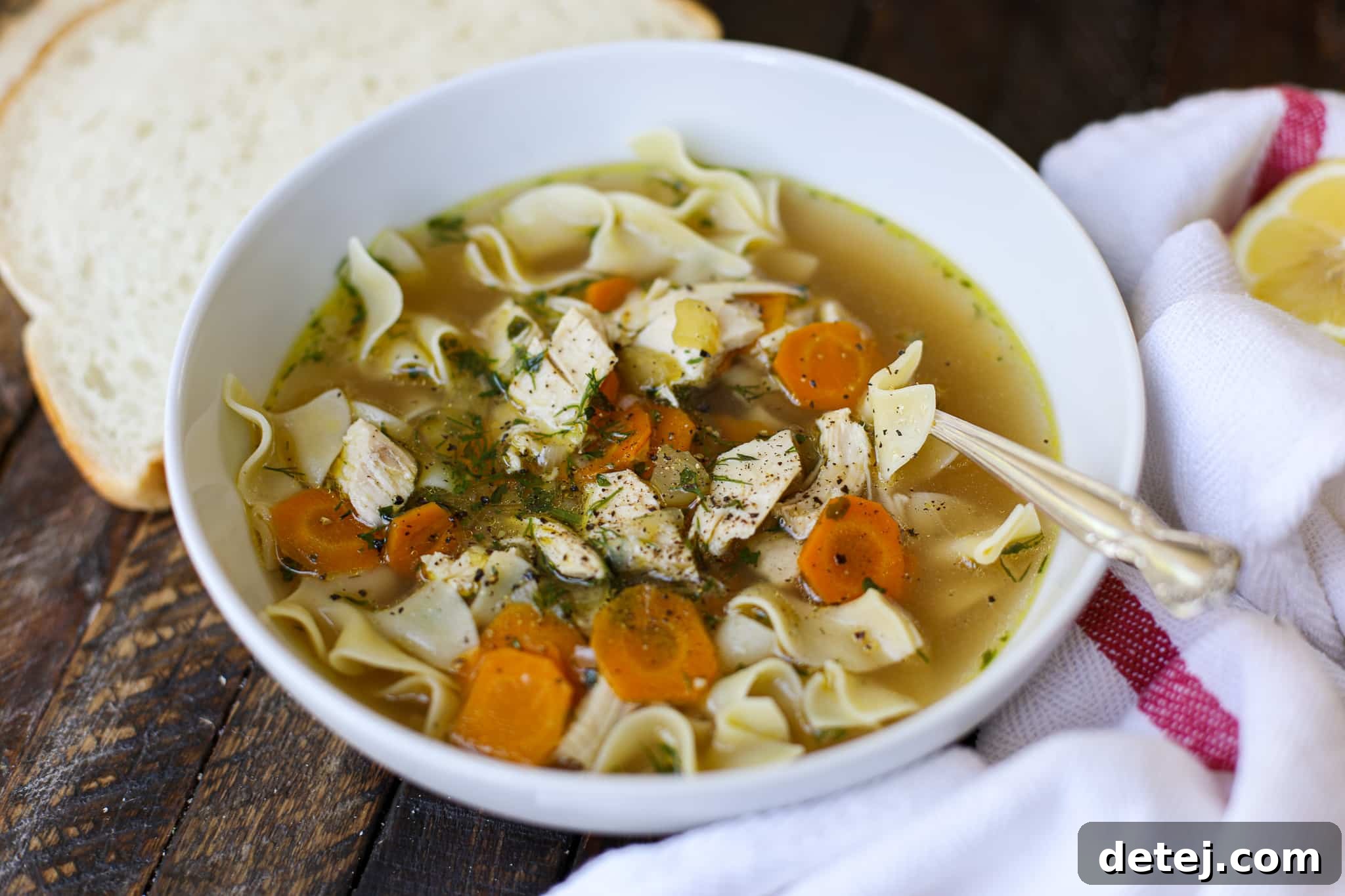 A steaming bowl of Bone Broth Chicken Noodle Soup garnished with fresh herbs