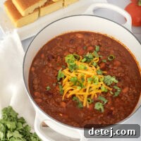 A close-up of a finished bowl of stovetop chili with toppings.