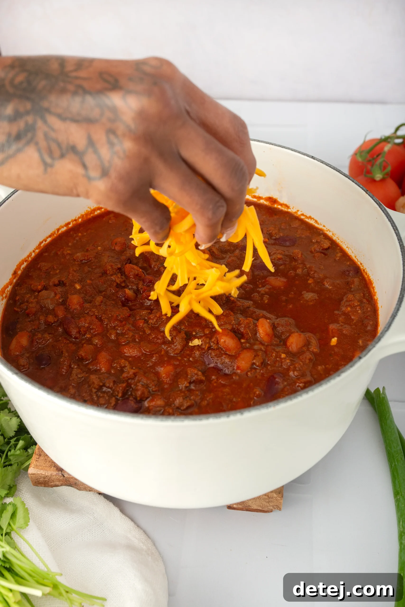 A vibrant selection of fresh ingredients for chili, including neatly diced onions, sliced bell peppers, and various canned beans, arranged on a rustic wooden surface.