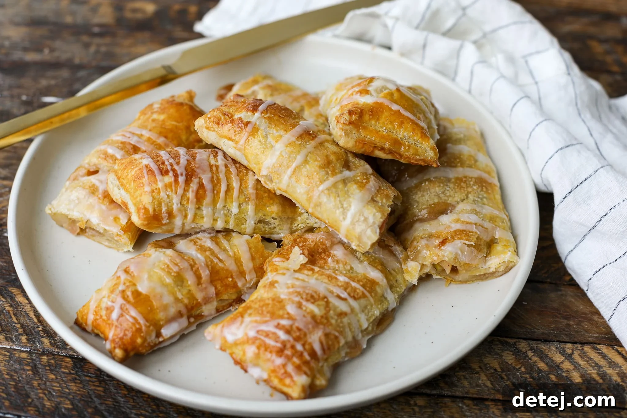 Close-up of baked Apple Strudel Logs, drizzled with white icing.