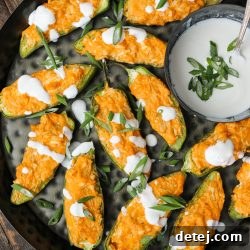 A freshly baked batch of Buffalo Chicken Jalapeno Poppers on a wooden board, garnished with green onions.