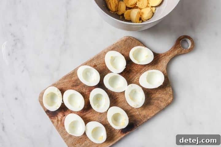 Hard-boiled eggs sliced in half with yolks carefully removed and placed in a separate bowl.
