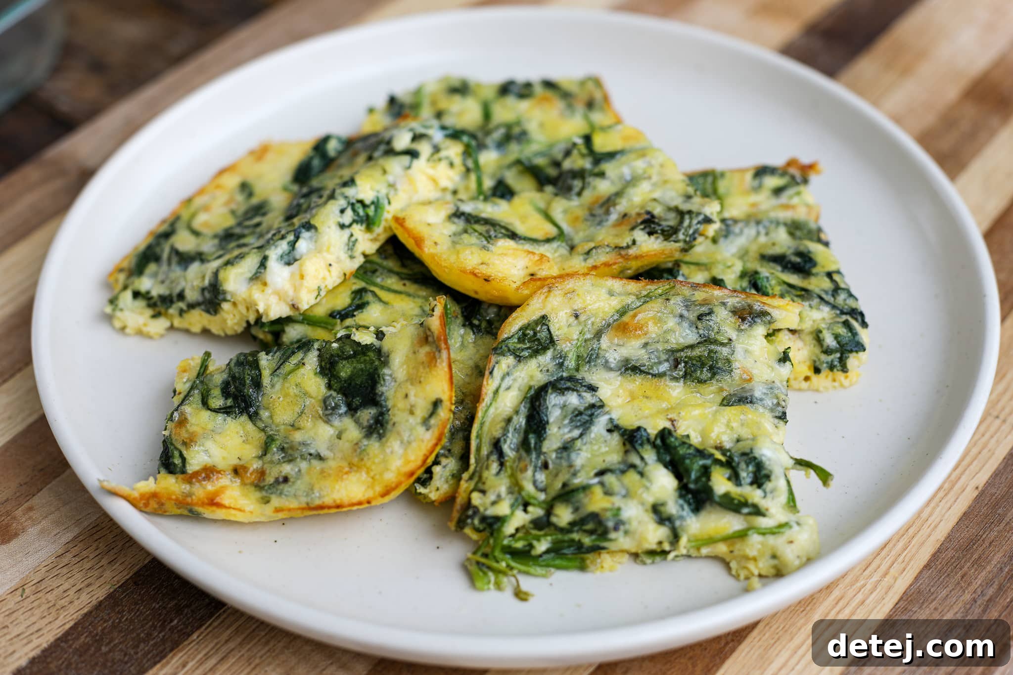 Savory Spinach and Cheesy Baked Eggs 4 Freshly baked Cheesy Spinach Baked Eggs sliced and ready to serve, showing the delicious layers of egg, cheese, and spinach. Perfect for a hearty breakfast or brunch.