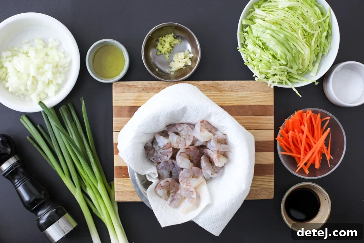 Egg Roll Stir-Fry Bowl 3 Ingredients for Egg Roll in a Bowl laid out on a cutting board, including fresh shrimp, cabbage, carrots, onion, garlic, and ginger.