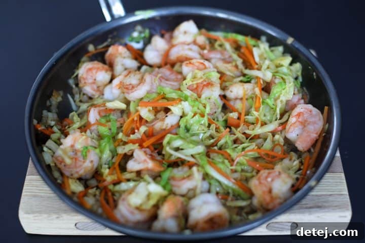 Egg Roll Stir-Fry Bowl 5 The vibrant egg roll in a bowl mixture of shrimp and sautéed vegetables in a pan.