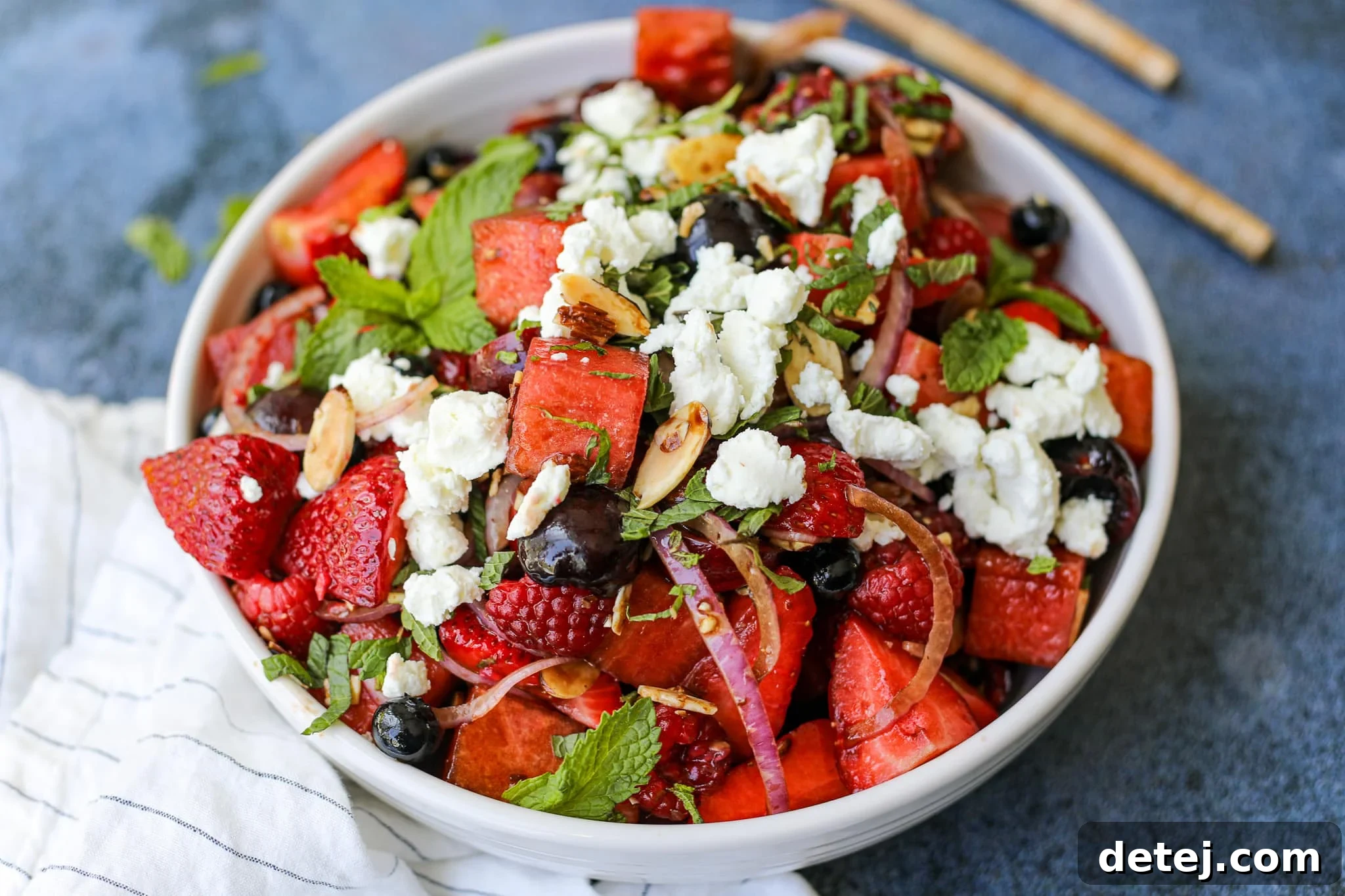 Vibrant Summer Refreshment 4 A beautifully presented Summer Fruit Salad in a glass bowl, garnished with fresh mint and goat cheese. Healthyish Foods.