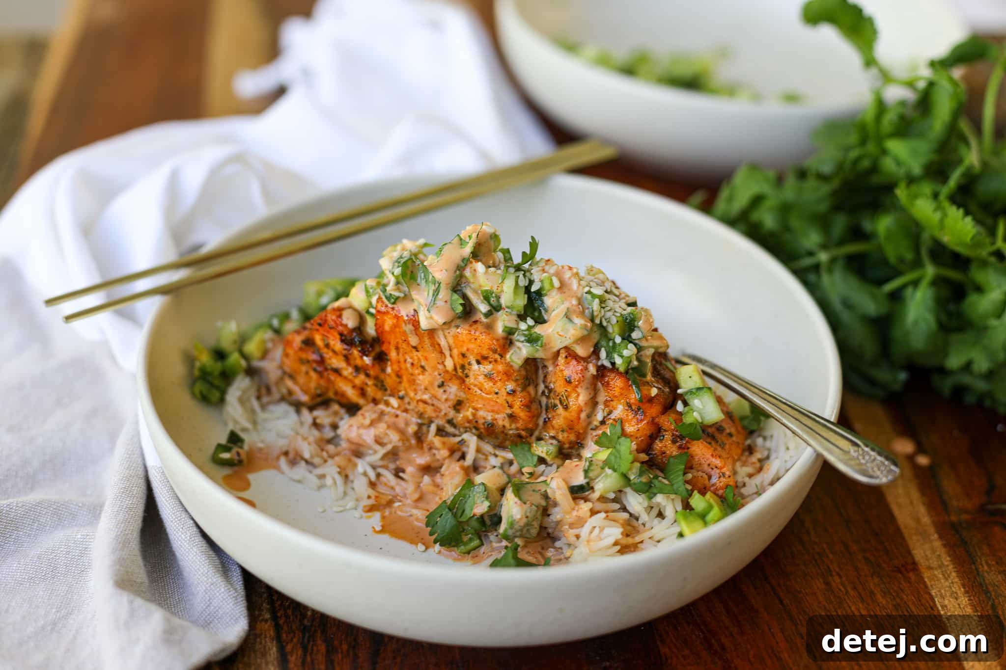 Air Fryer Spicy Hasselback Salmon plated with fresh salad, sauce, and sesame seeds.