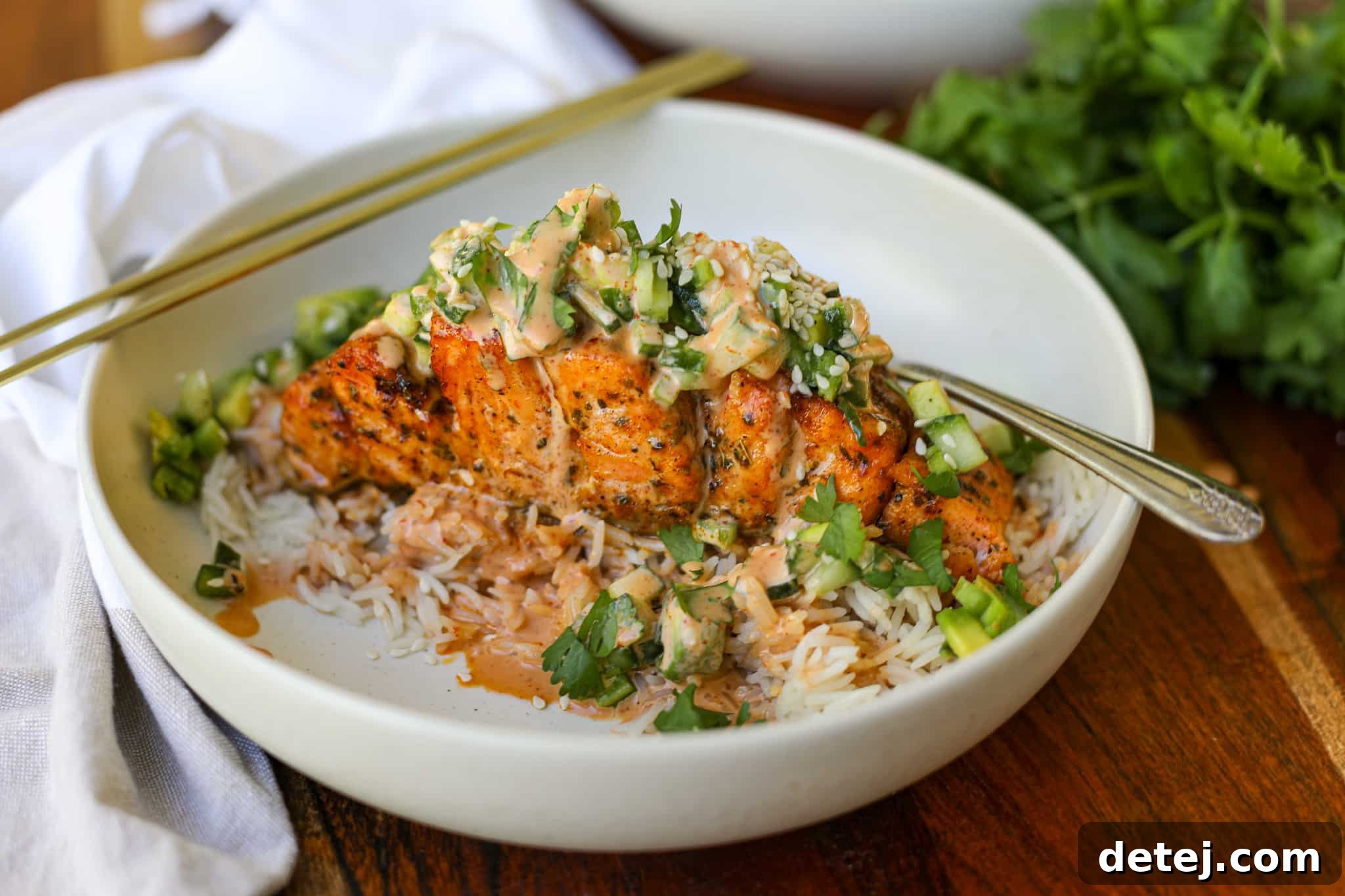 Air Fryer Spicy Hasselback Salmon, ready to be served over rice with salad and sauce.