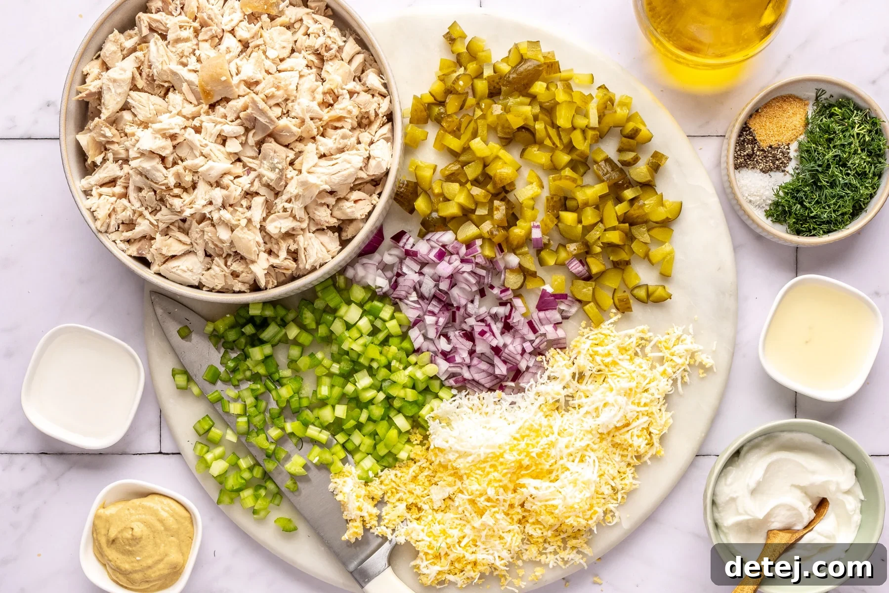 Collection of fresh ingredients for dill pickle chicken salad, including chicken, pickles, celery, and herbs.